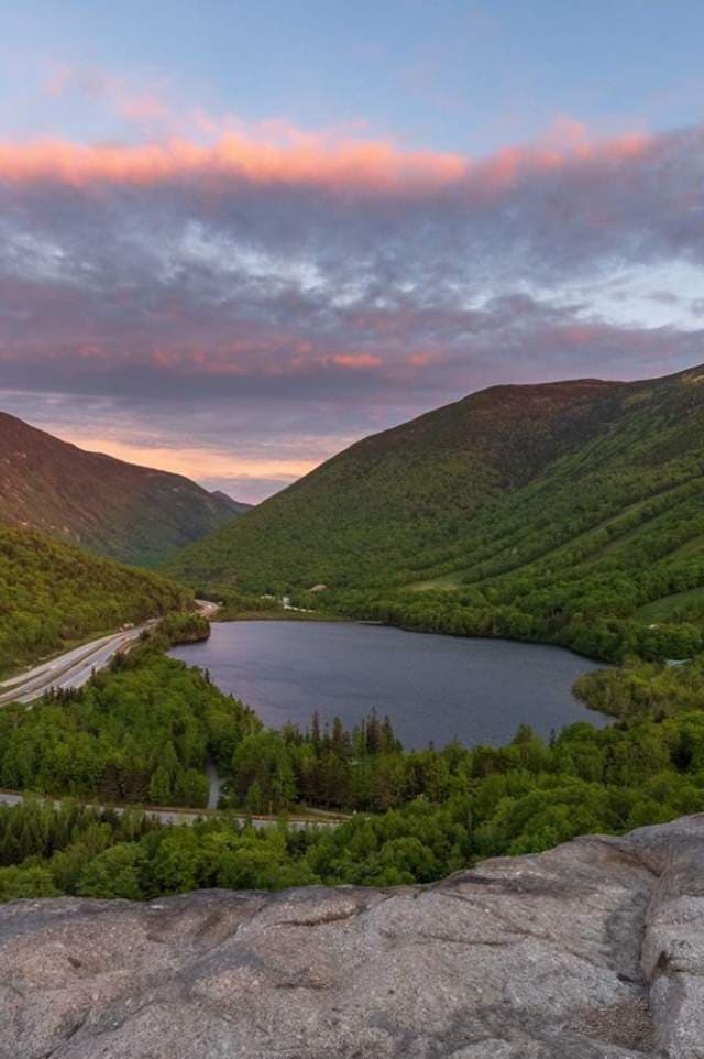 A mountain lake below a pink sunset sky, original
